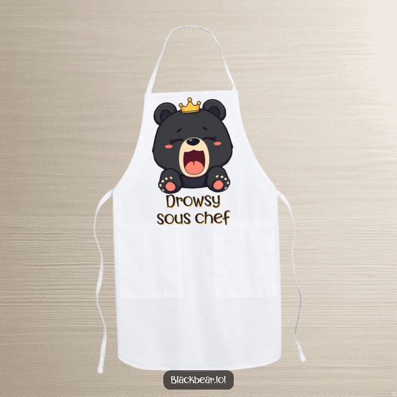 Funny sleepy black bear cub apron depicting a cub yawning with a tilted crown, adding humor to kitchen tasks.