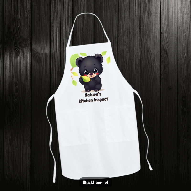 Funny apron with a black bear cub's wide, curious eyes inspecting a shimmering leaf, bringing a touch of woodland charm to cooking.
