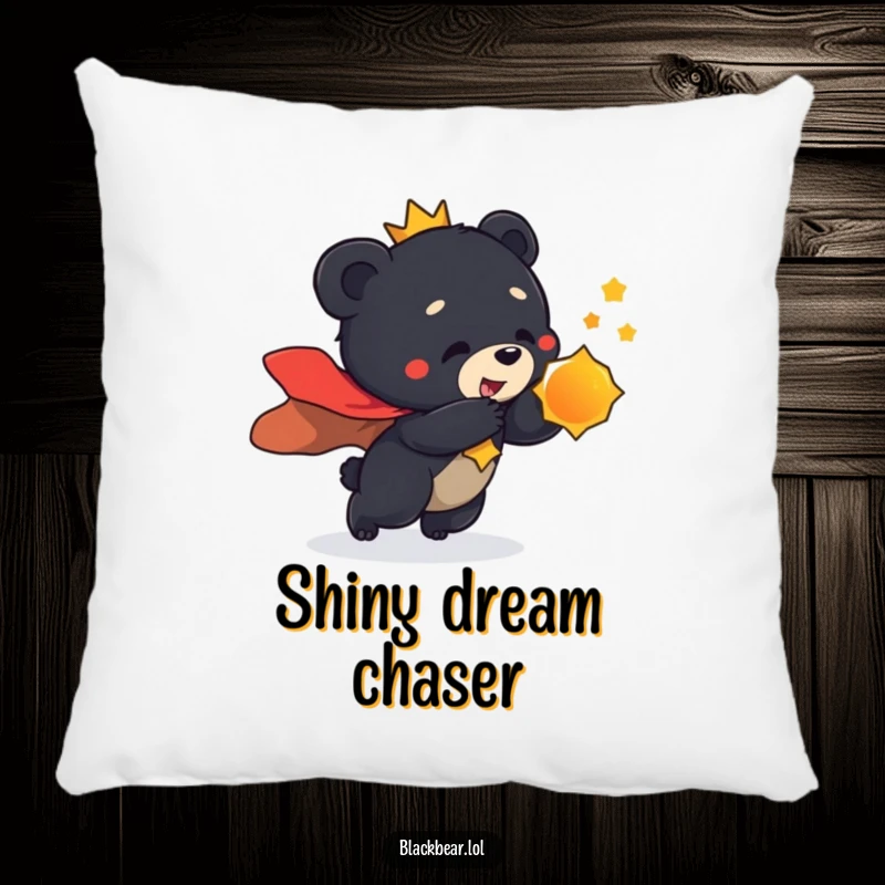 Funny pillow design of a black bear cub wearing a regal cape, playfully lunging towards a shiny object.