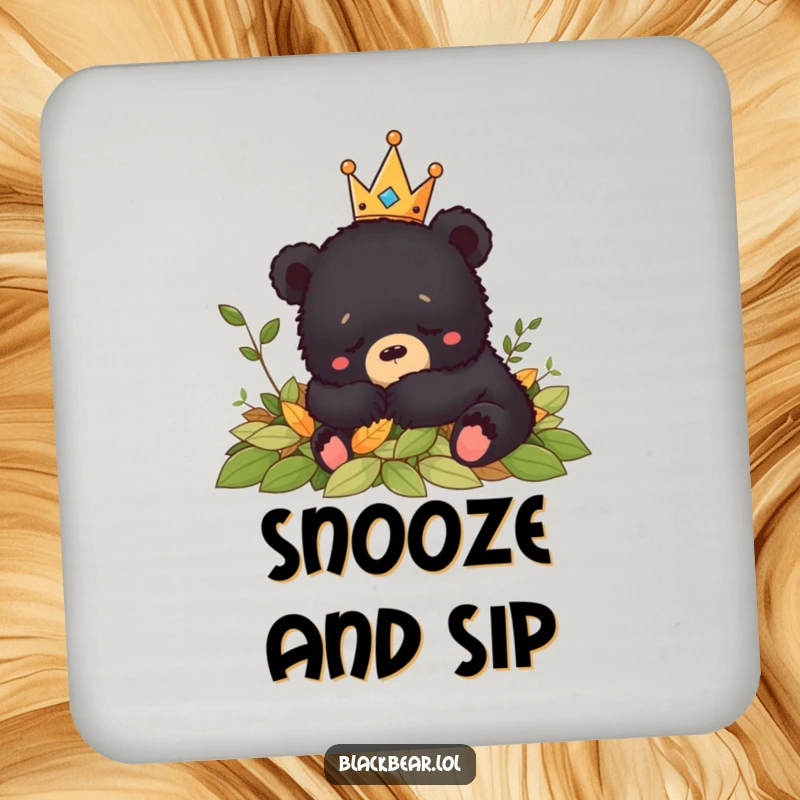 Funny crowned black bear cub napping peacefully in leaves, adding a humorous and calming touch to this drink coaster.