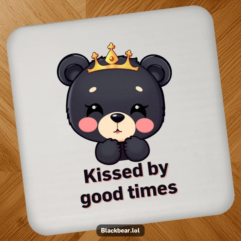 Funny black bear cub coaster, a cub in a sparkly crown blowing a kiss downwards, adding sweet humor to tabletops.