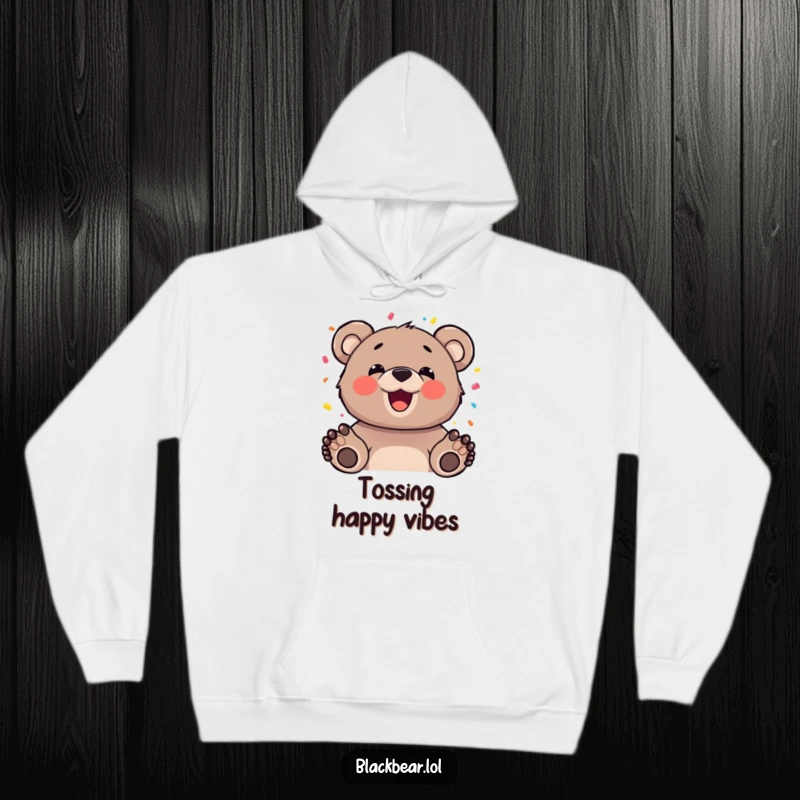 Funny bear cub with a happy expression tossing confetti, depicted on a cozy hoodie, offering warmth and festive cheer.