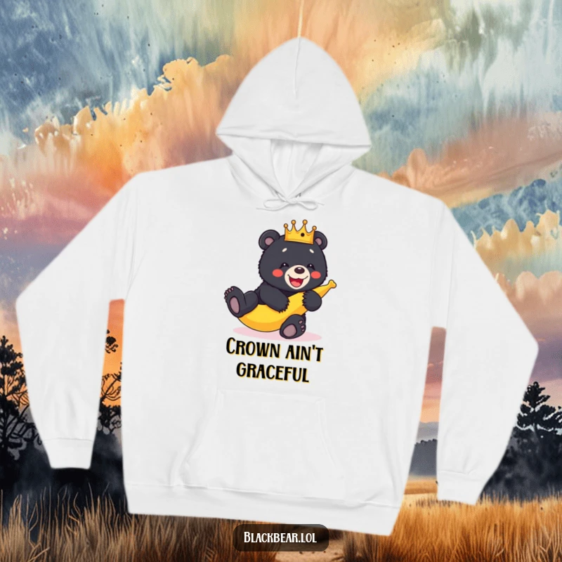 Funny crowned black bear cub in a comical pose slipping on a banana peel, captured on a warm hoodie.
