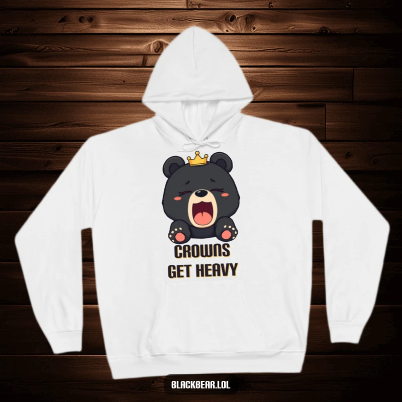 Funny sleepy black bear cub hoodie depicting a cub yawning with a tilted crown, symbolizing royal fatigue and comfort.