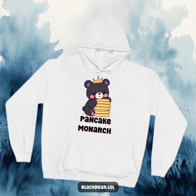 Funny black bear cub wearing a crown balances a stack of pancakes, showcasing impressive skill on this cozy hoodie.