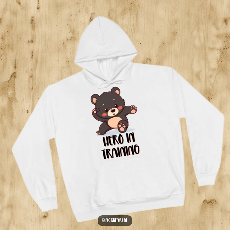 Funny hoodie featuring a black bear cub striking a heroic pose but slightly losing its balance, offering warmth and relatable humor.
