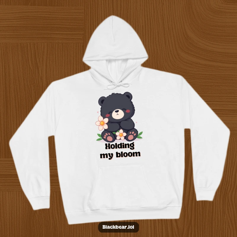 Funny hoodie featuring a content black bear sitting peacefully, holding a large flower, offering warmth and a sense of calm.