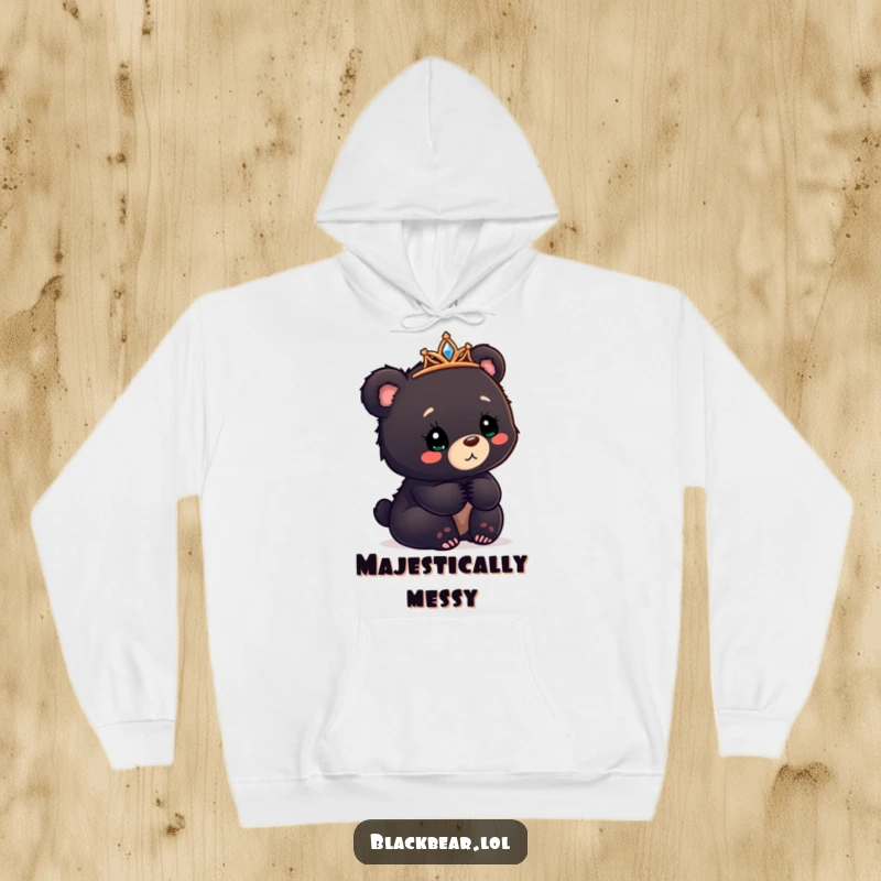 Funny black bear cub hoodie with a tiara askew, looking confusedly delighted, cozy and whimsical comfort.