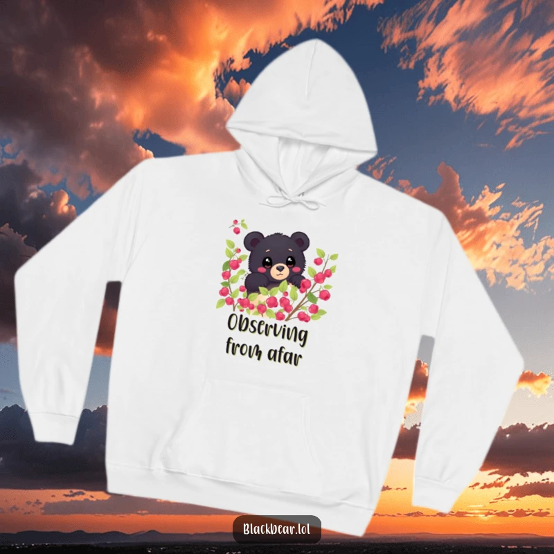 Funny shy black bear peeking from behind a berry bush, eyes wide with wonder on a warm hoodie. Curious and humorous forest creature.