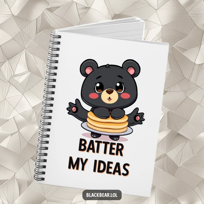 Funny notebook with a cover showing a stylized black bear with big eyes, comically balancing a stack of pancakes.
