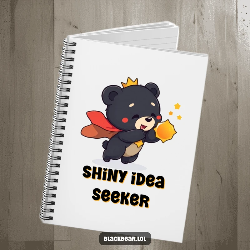 Funny notebook cover featuring a black bear cub in a regal cape, playfully lunging towards a shiny object, perfect for notes.
