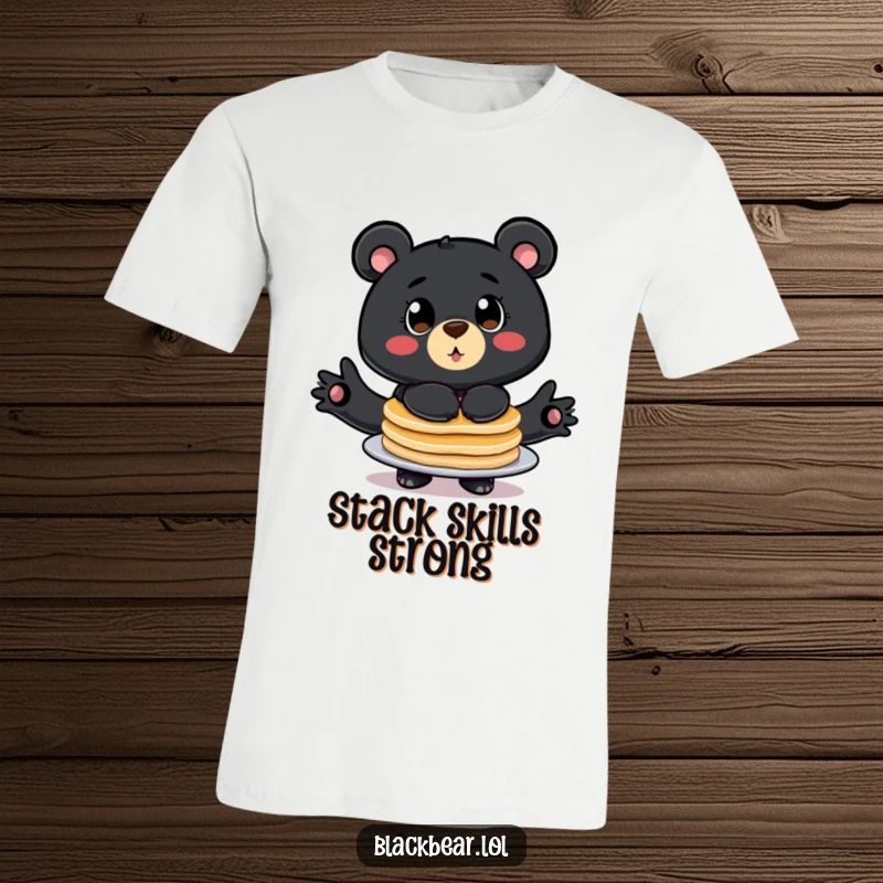 Funny t-shirt with a stylized black bear, big eyes wide, comically balancing a huge stack of pancakes.