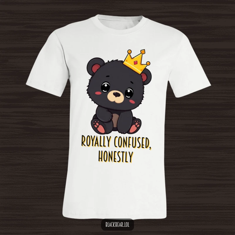 Funny t-shirt depicting a black bear cub wearing a tiny crown and looking surprised, representing cute royalty and unexpected moments.
