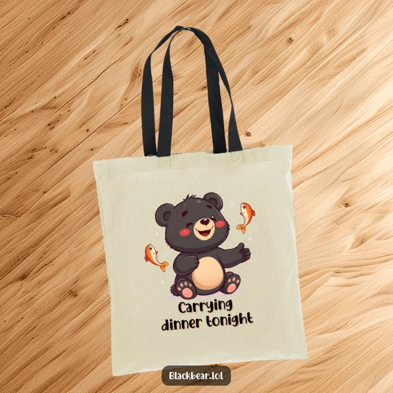 Funny tote bag showing a smiling black bear cub juggling fish with a bewildered expression, practical and humorous.