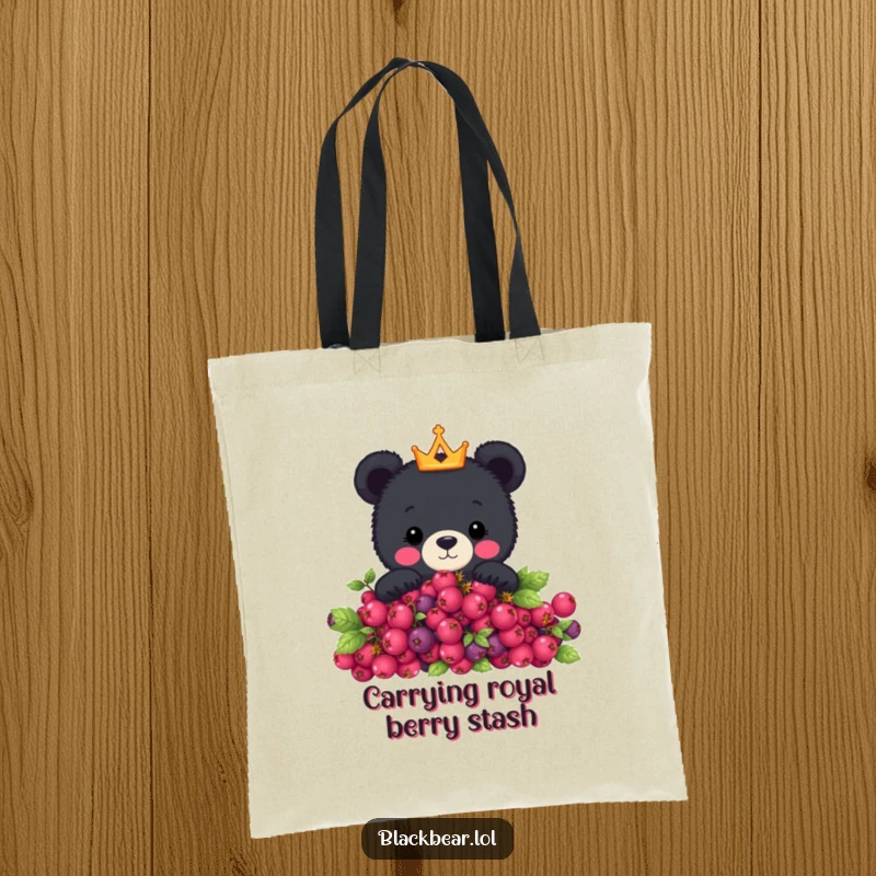 Funny tote bag with a cute black bear wearing a tiny crown peeking over a berry bush, perfect for stylish and humorous everyday use.