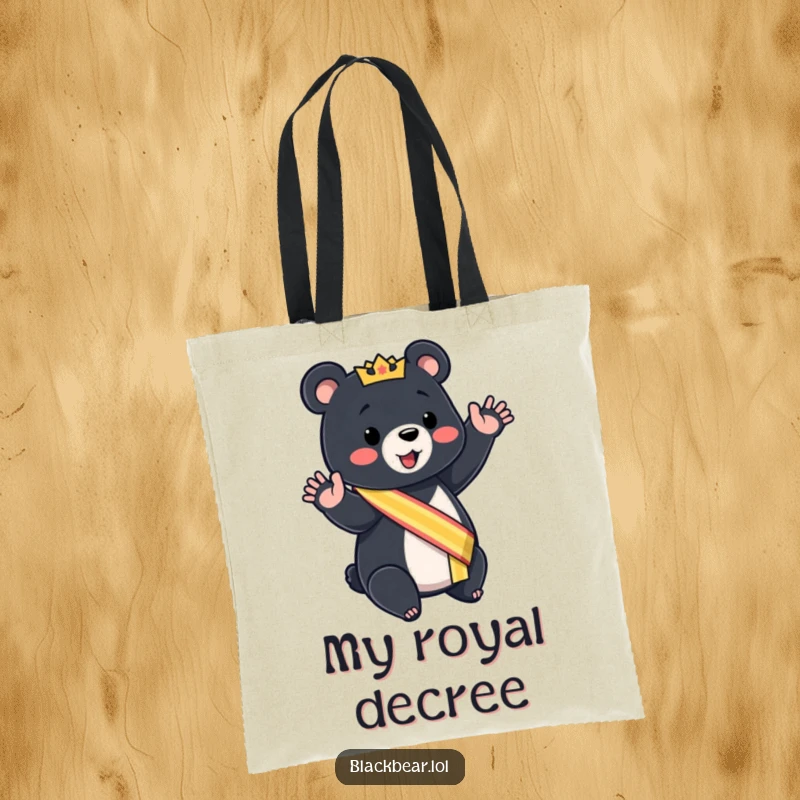 Funny black bear cub tote bag wearing a sash, giving a mock royal wave, stylish and humorous.